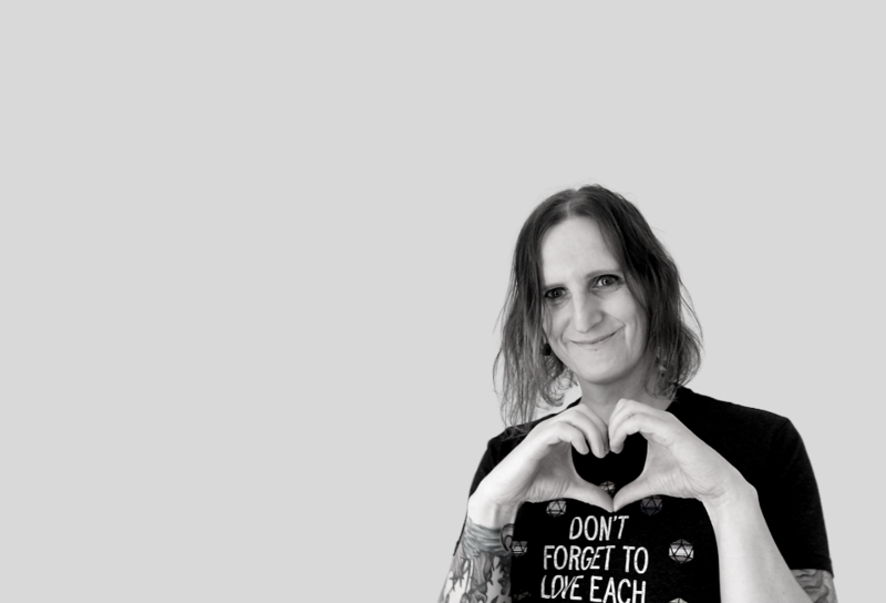 Dr Clara Barker placed off centre, making a love heart shape with her hands and wearing a T-shirt with the legend DON'T FORGET TO LOVE EACH OTHER
