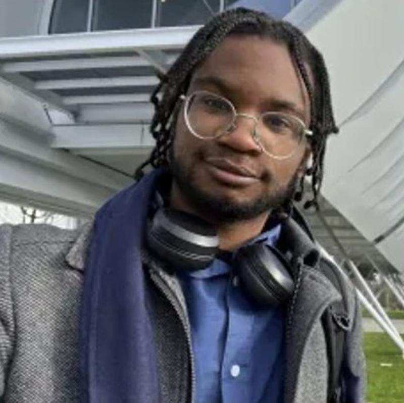 Joseph Fihosy standing outside a scientific building, and smiling at the camera