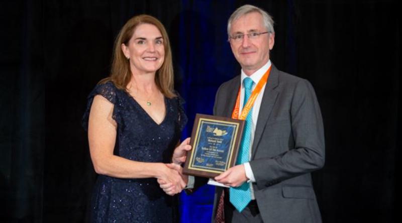 Professor Richard Todd holding his Fellowship plaque and shaking hands with an official from the ACS
