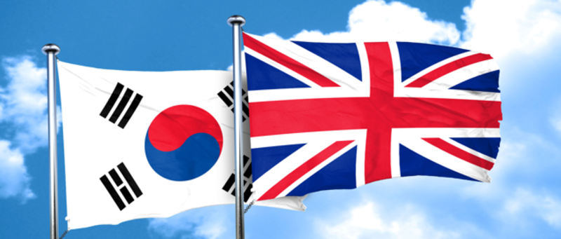 The South Korean and Union 'Jack' flags flying on flagpoles against a blue sky