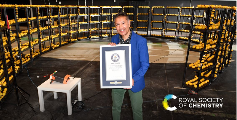 Prof Saiful Islam standing in front of his lemon powered battery and holding the Guinness World Record certificate