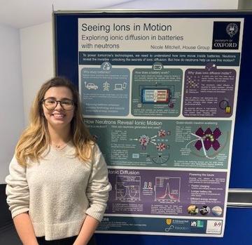 Nicole Mitchell, smiling, and standing next to her prize winning poster