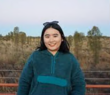 Rruomu Zhang standing with a cityscape behind her